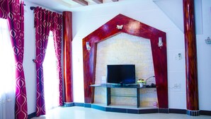 Una sala de estar moderna con chimenea de piedra, televisor de pantalla plana y cortinas rojas.