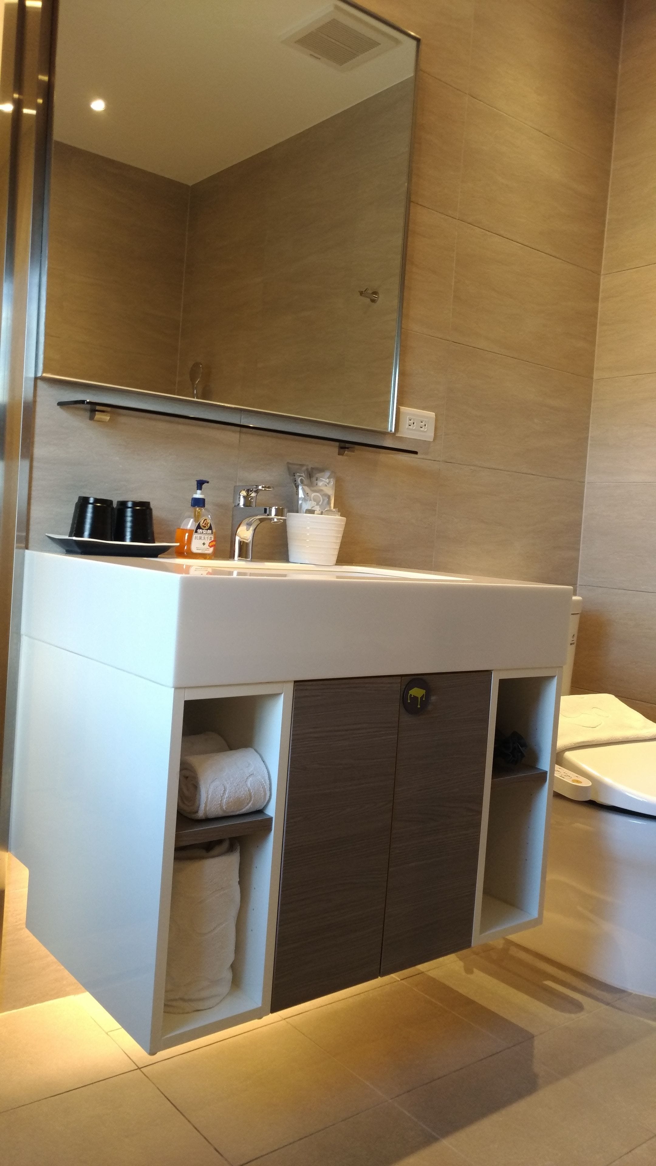 Un baño moderno con un tocador blanco, un espejo e inodoro empotrado.