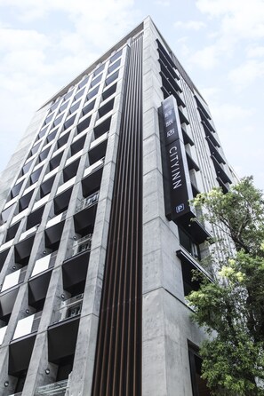 A high-rise building with a modern architectural design, featuring a prominent vertical column and a sign indicating it is a parking facility. - Cityinn Hotel Plus Fuxing N. Rd. Branch (Taipei)