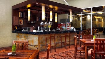 A bar area with wooden chairs and tables, a counter with various items, and a patterned floor.