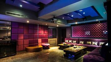 A modern lounge area with a red and black color scheme, featuring a sofa, a coffee table, and a jukebox.