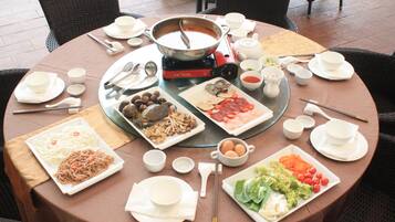 A round dining table with various dishes and a hot pot in the center.