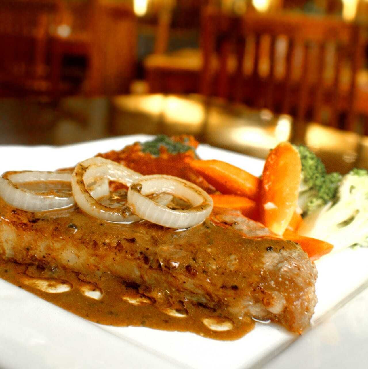 A plate of food with a fish fillet, vegetables, and a sauce.