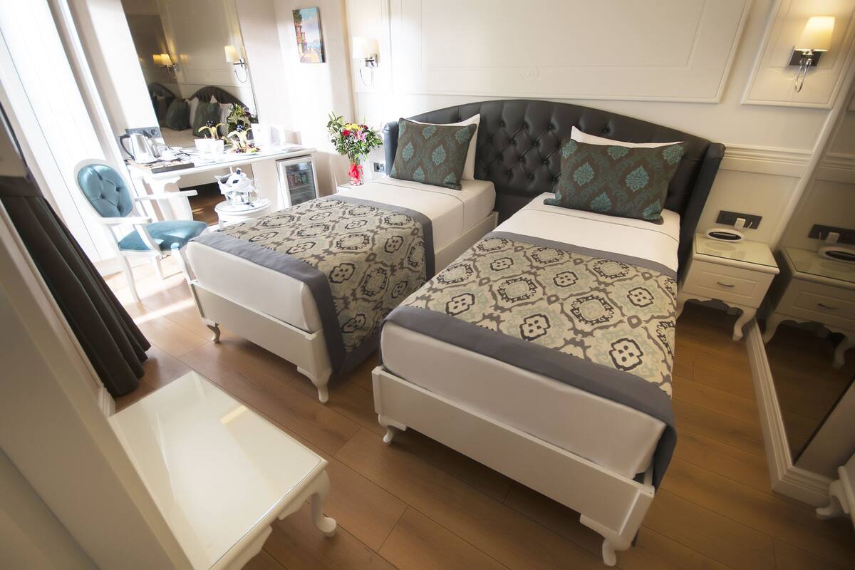 Ein Hotelzimmer mit zwei Betten, einem Schreibtisch, einem Stuhl und einem kleinen Tisch.