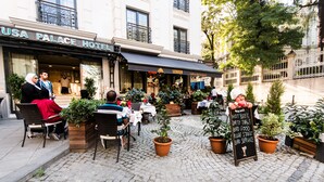 An outdoor seating area with tables and chairs, potted plants, and a signboard with a menu. - Antusa Palace Hotel & Spa (Istanbul)