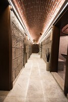 A corridor with a brick ceiling, stone walls, and a marble floor.
