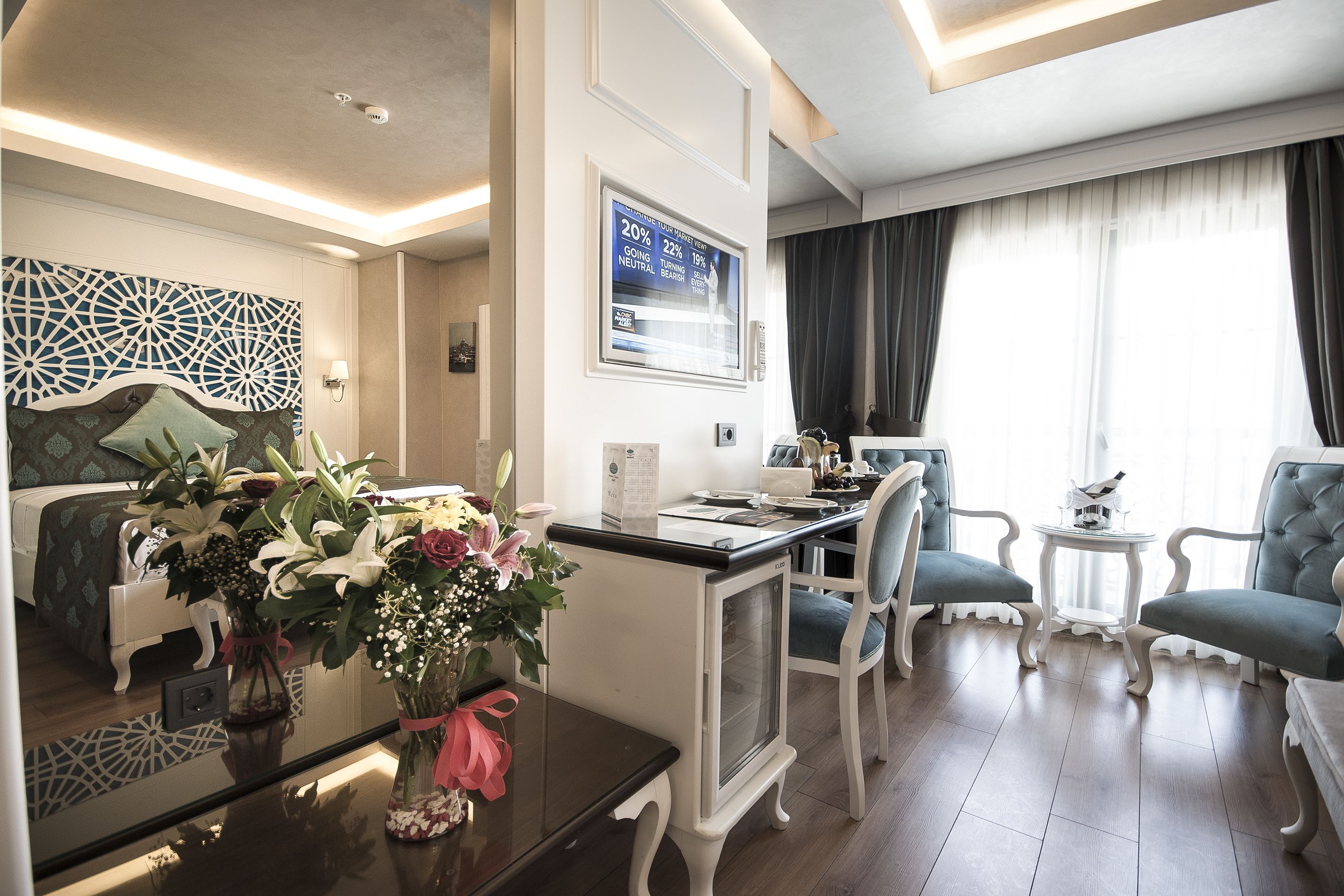 A modern hotel room with a dining area, a TV, and a view of the outdoors.