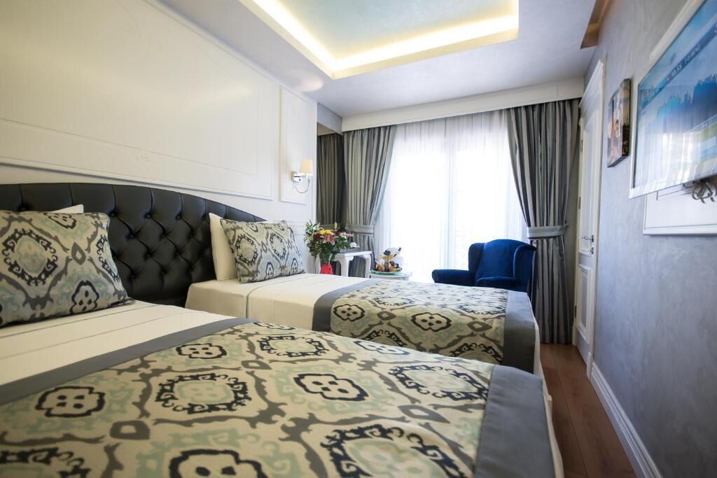 Una habitación de hotel con una cama grande, una cama más pequeña, un escritorio y una silla.