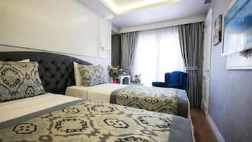 Una habitación de hotel con una cama grande, una cama más pequeña, un escritorio y una silla.