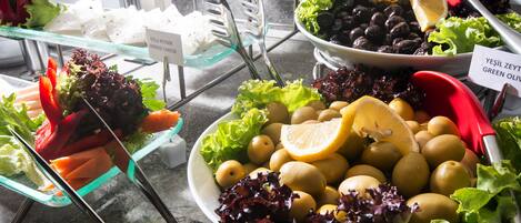 A buffet with various food items including vegetables, fruits, and cheese.