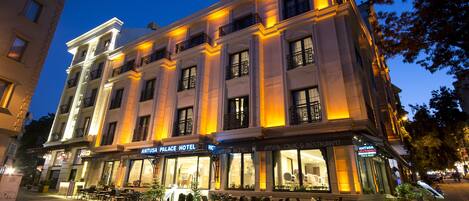 Um hotel com vários andares, área de estar ao ar livre e fachada bem iluminada.