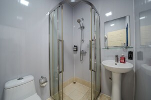 Ein modernes Badezimmer mit einer Duschkabine, einer Toilette, einem Waschbecken und einem Spiegel.