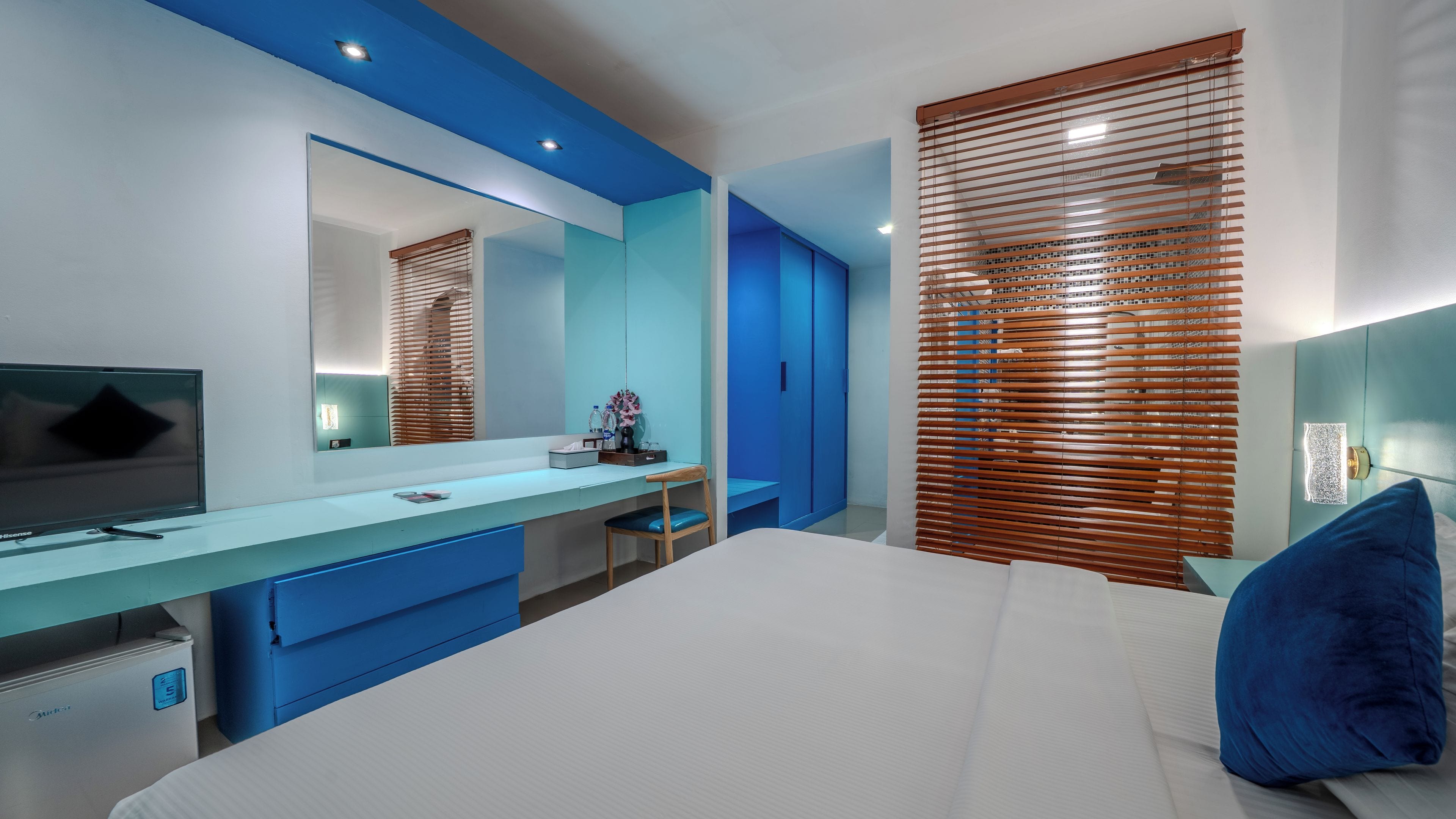 A modern bedroom with a large bed, a bedside table, a TV, a mirror, and a wardrobe.