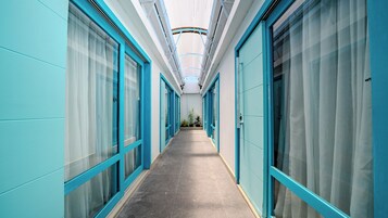 A corridor with glass doors and windows, leading to a room with a ceiling light fixture.