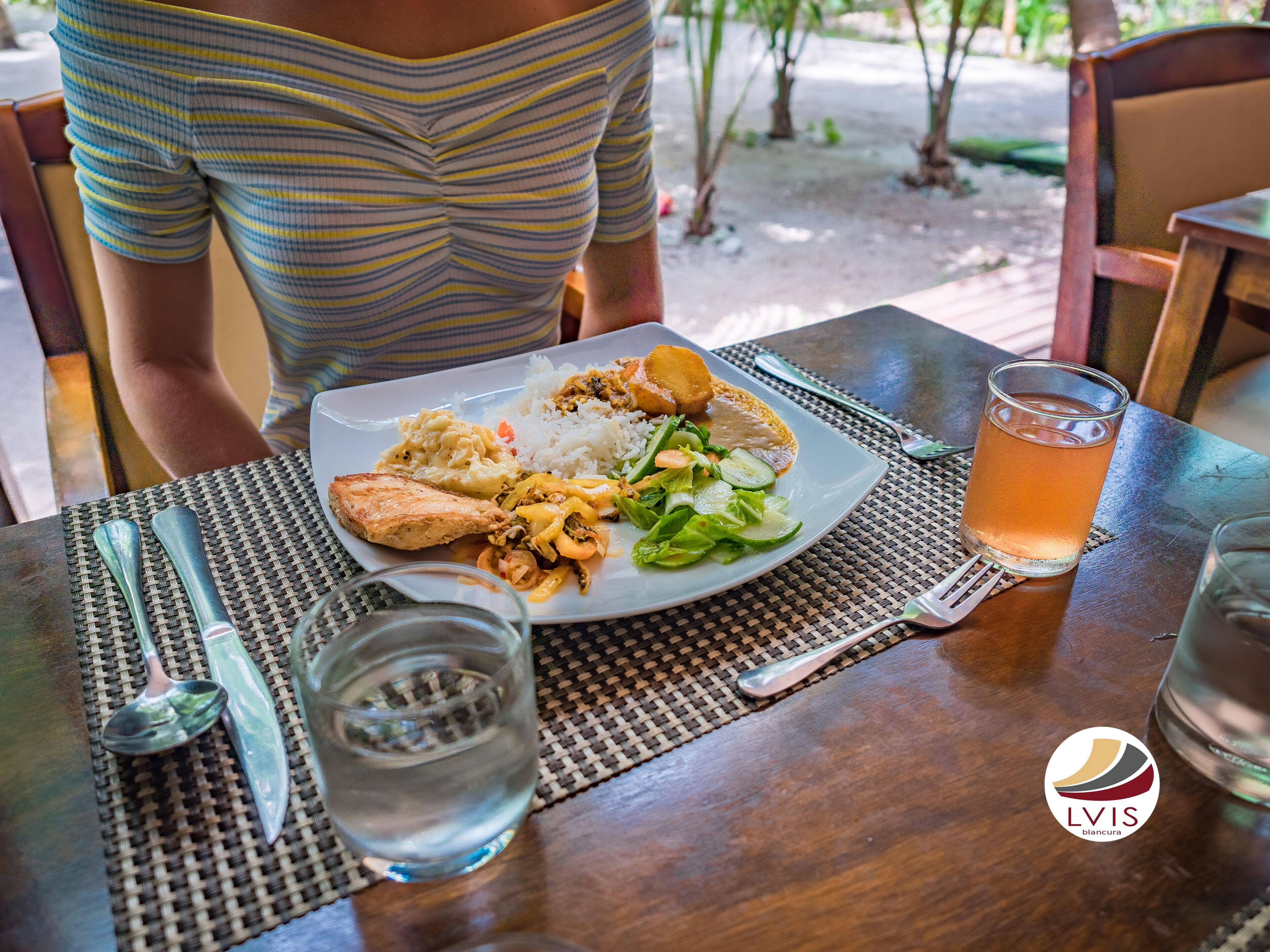 A dining table with a plate of food, a glass of iced tea, and a water glass.