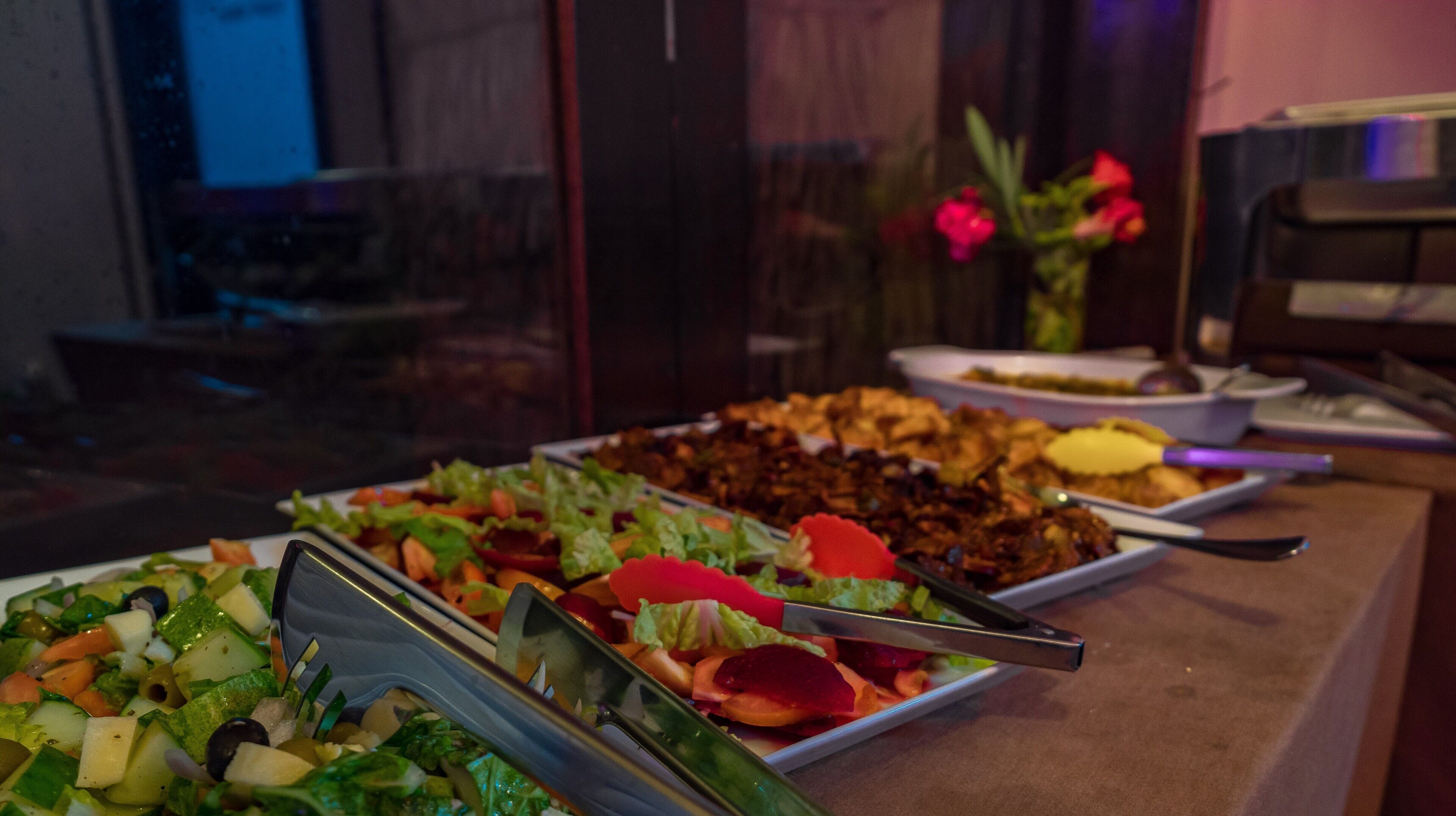 A buffet table with various dishes, including salads and a dessert.