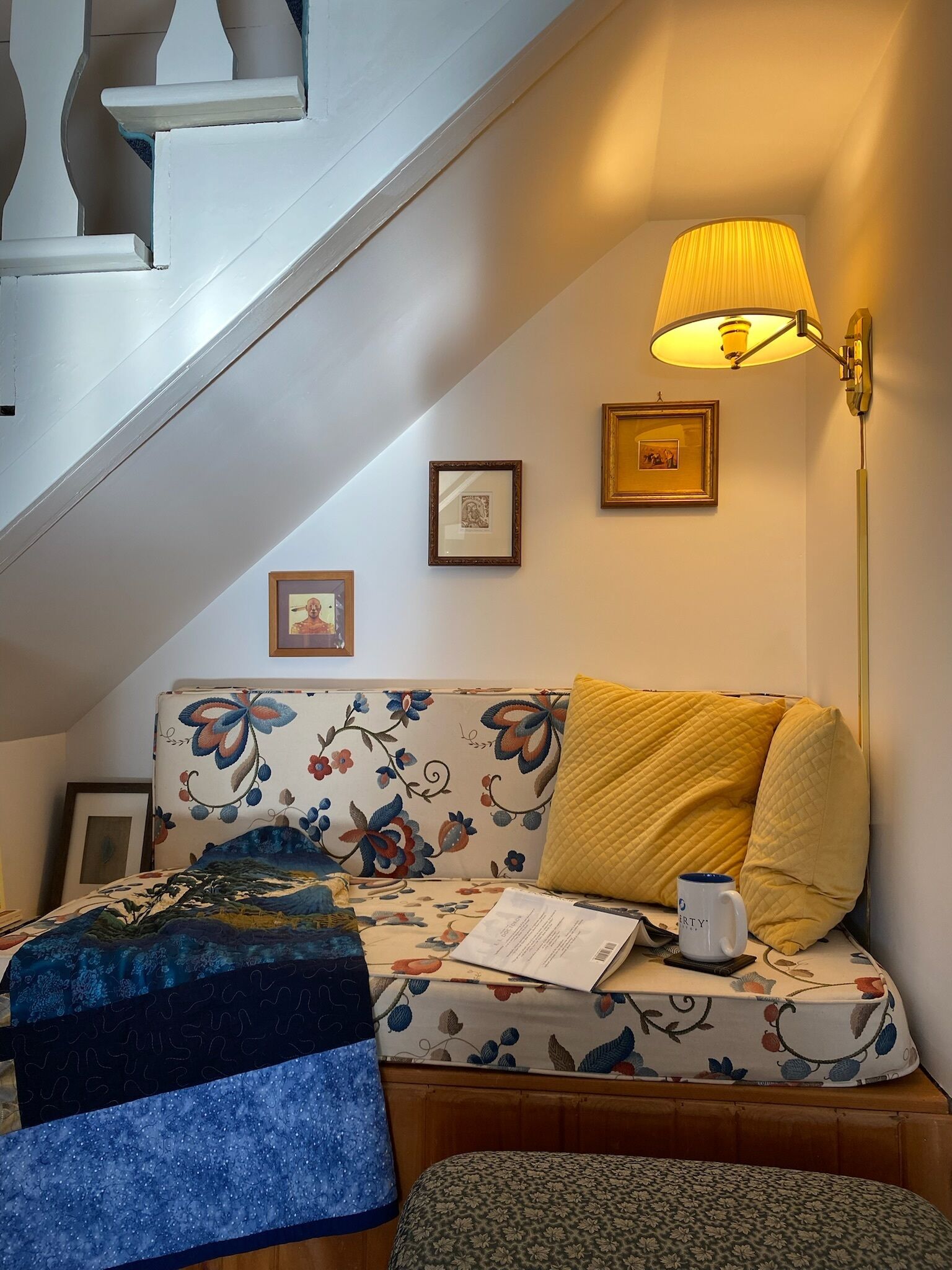 Een gezellige kamer met een bank, een tafeltje, een lamp en een trap.