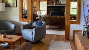 Una sala de estar acogedora con un sillón gris, suelo de madera y una chimenea de piedra.