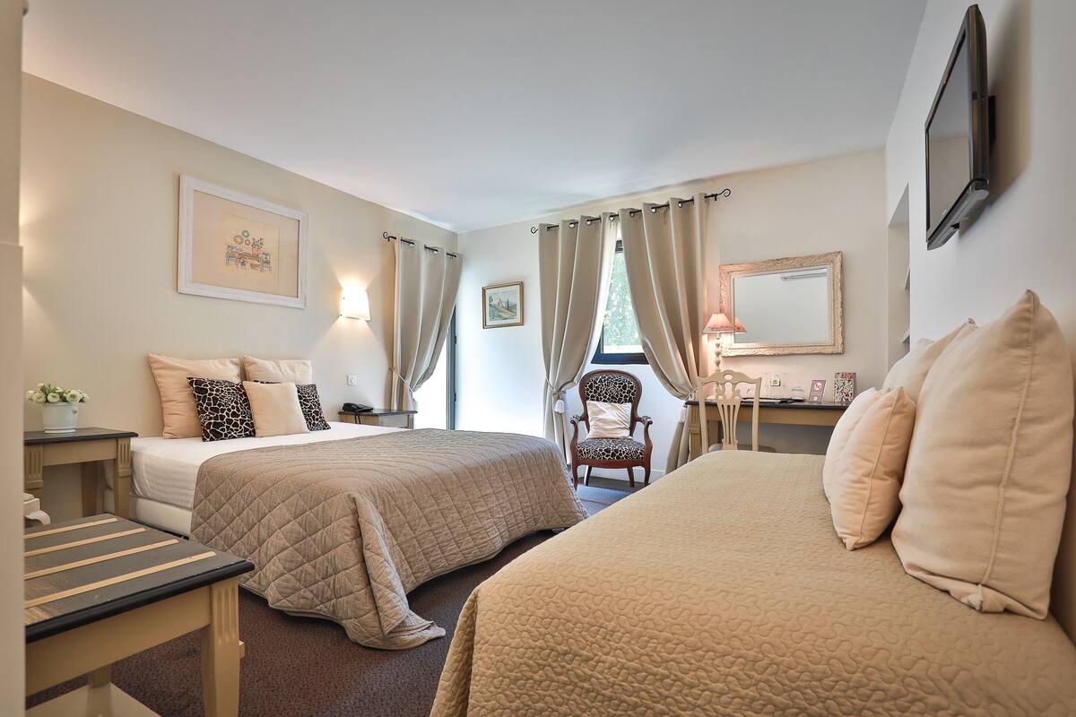 Una habitación de hotel con dos camas, un escritorio, una silla y un televisor.