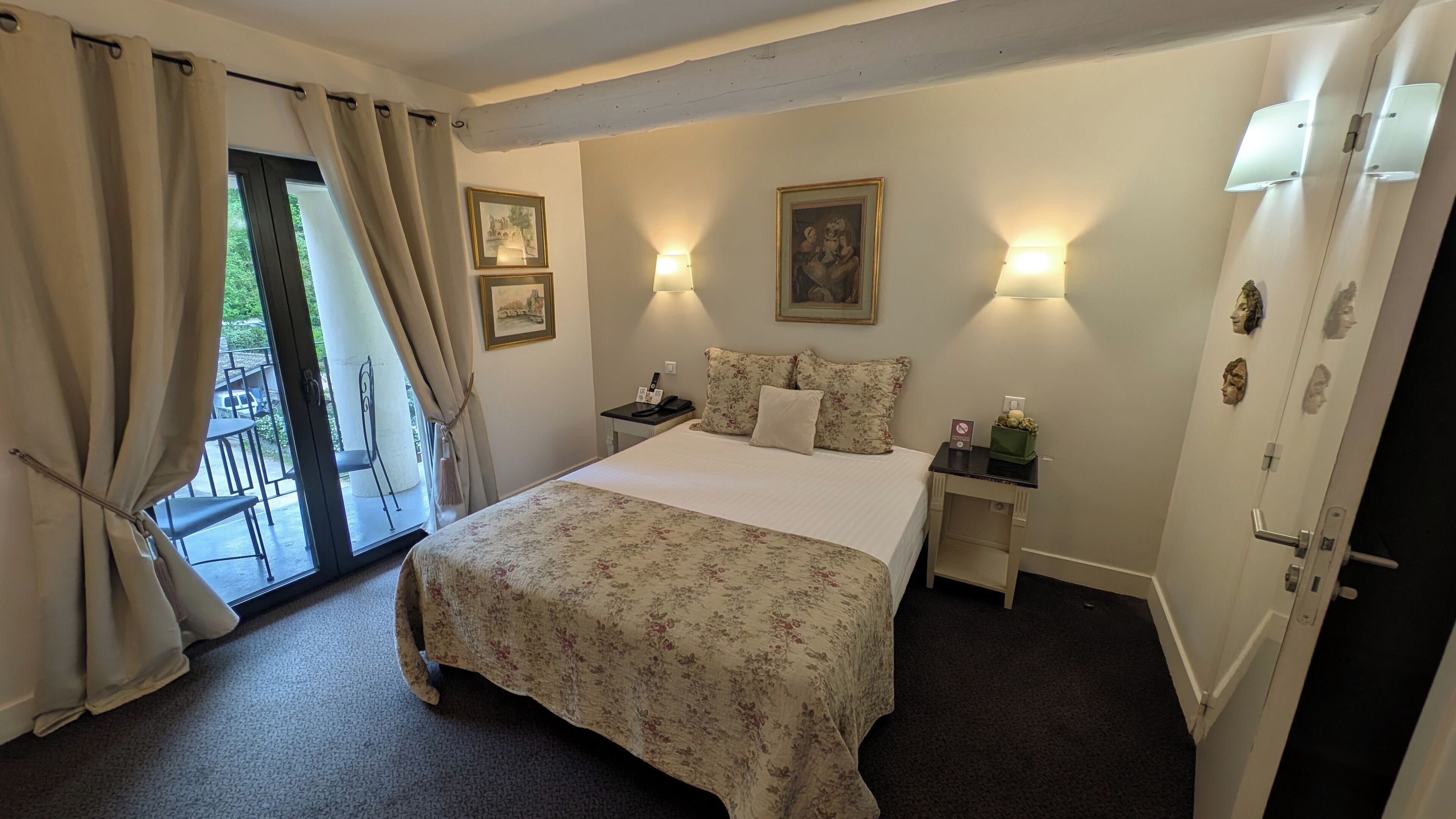 Une chambre d’hôtel comprenant un lit, deux tables de chevet, une commode, une porte et une vue sur l’extérieur.