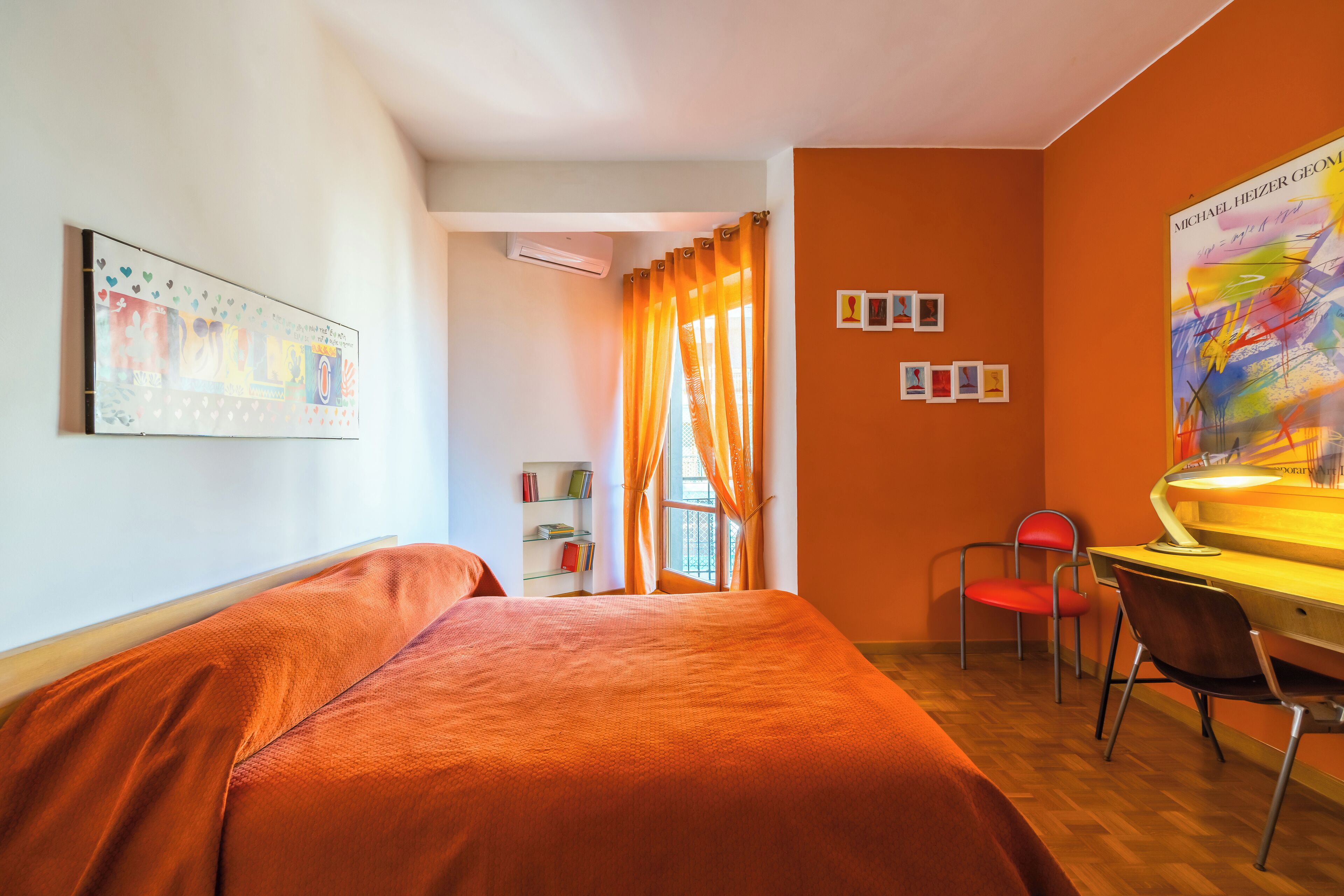 Ein Hotelzimmer mit Bett, Schreibtisch mit Stuhl, Klimaanlage und einem Vorhangfenster.