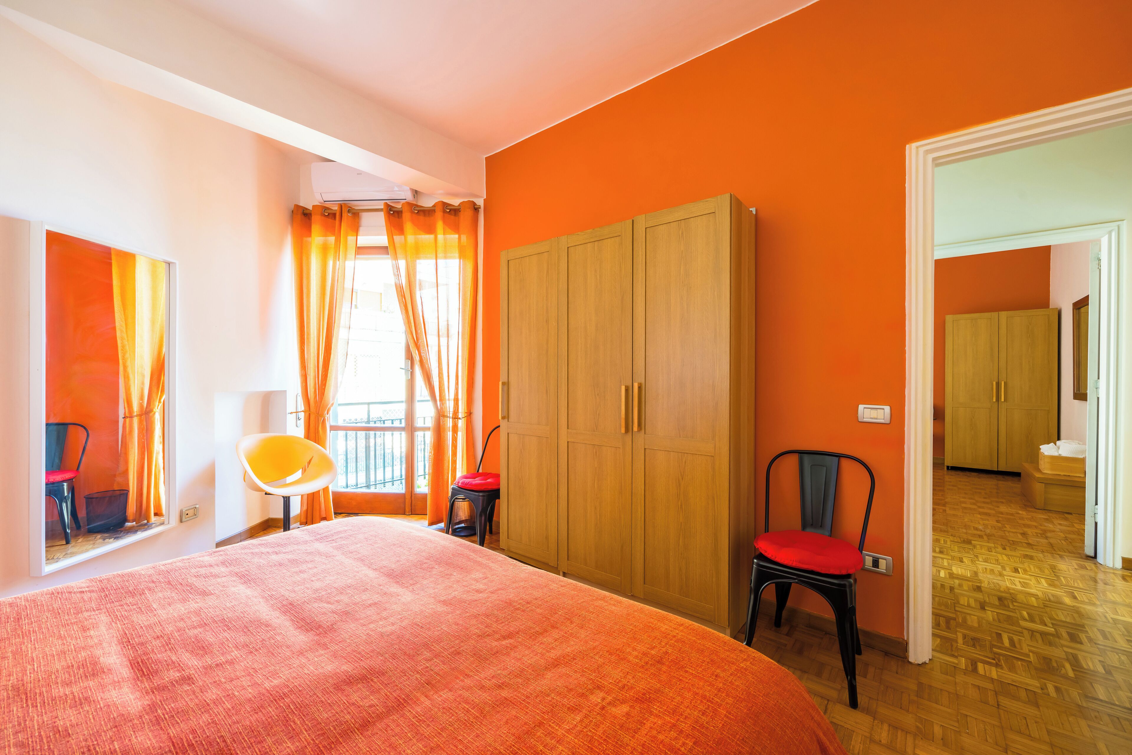 Ein Schlafzimmer mit einem großen Bett, einem Kleiderschrank, einem Stuhl und einem Fenster mit Vorhängen.