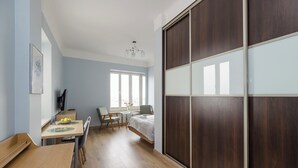 A bedroom with a bed, a desk with a chair, a small table with a chair, and a wardrobe. - ShortStayPoland Marszałkowska B188 (Warsaw)