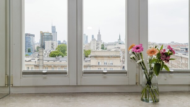 A window with a vase of flowers and a cityscape view. - ShortStayPoland Marszałkowska B188 (Warsaw)