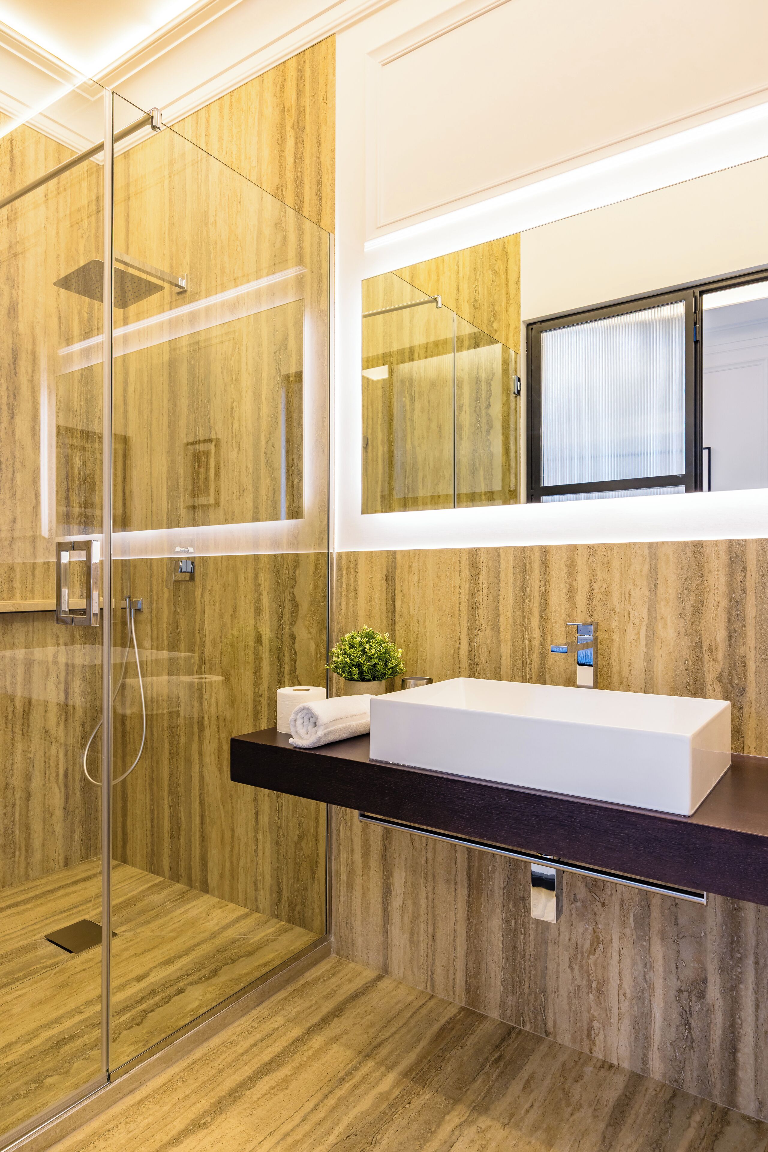 A modern bathroom with a glass shower enclosure, a white sink, and a wooden vanity.