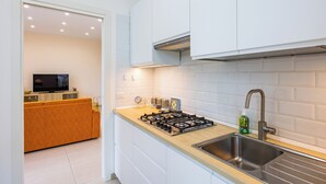 Una cocina moderna con armarios blancos, encimera de madera, estufa a gas y pileta de acero inoxidable.