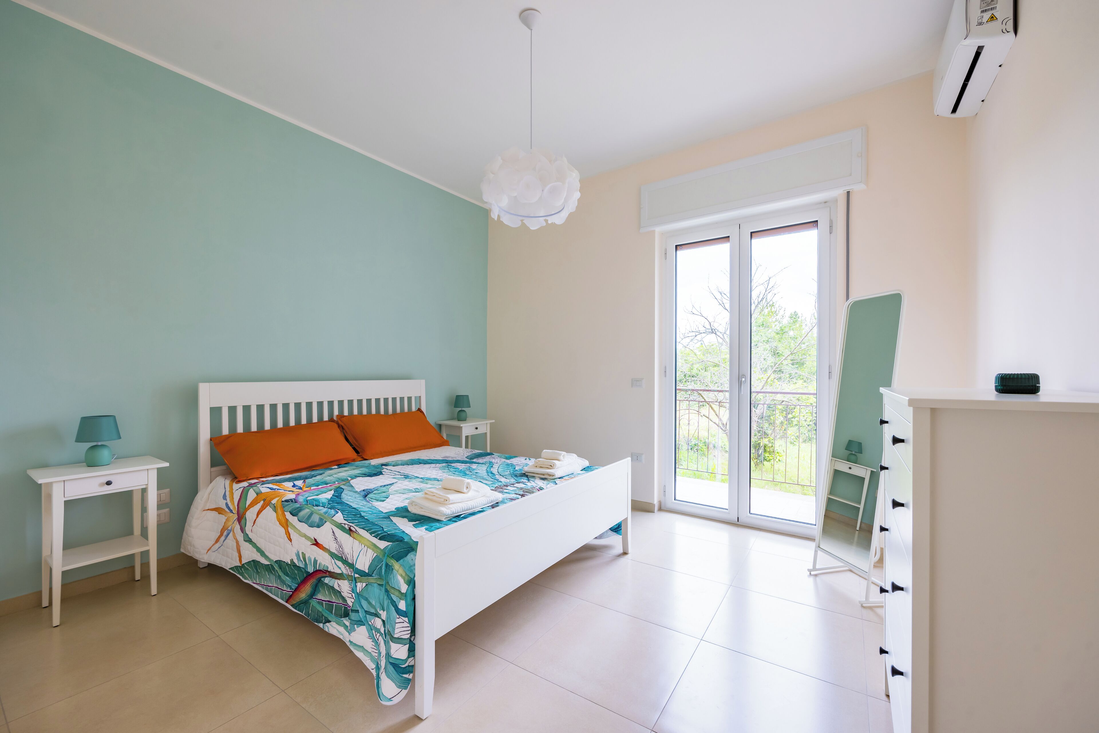 A bedroom with a bed, nightstands, a dresser, and a balcony.