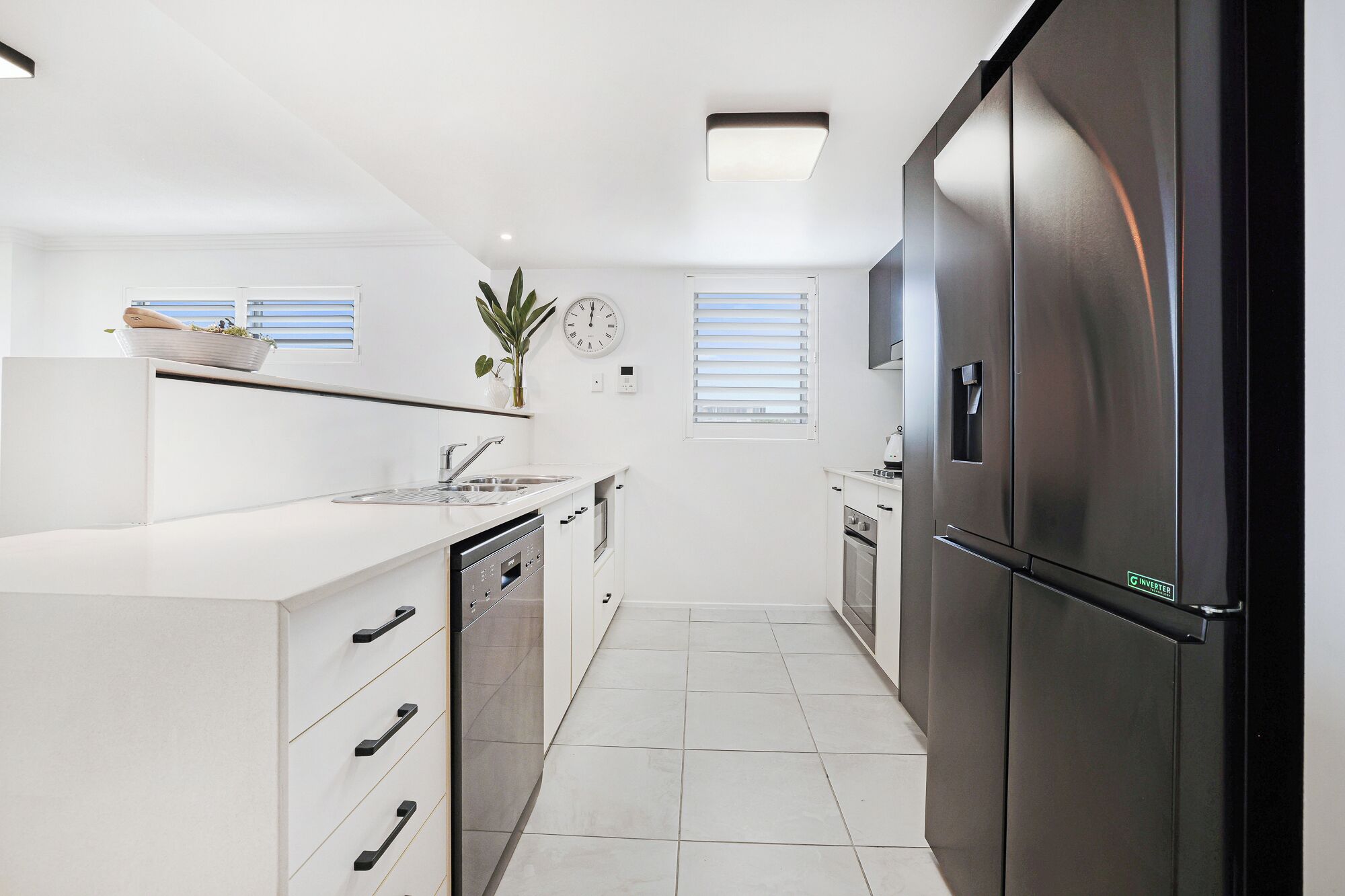 Una cocina moderna con armarios blancos, electrodomésticos de acero inoxidable y un refrigerador negro.