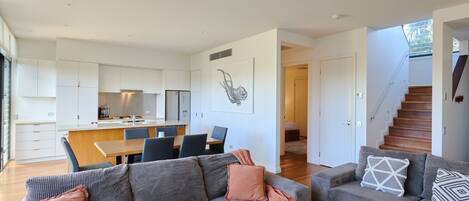 A modern living space with a kitchen, dining area, and two sofas with cushions.