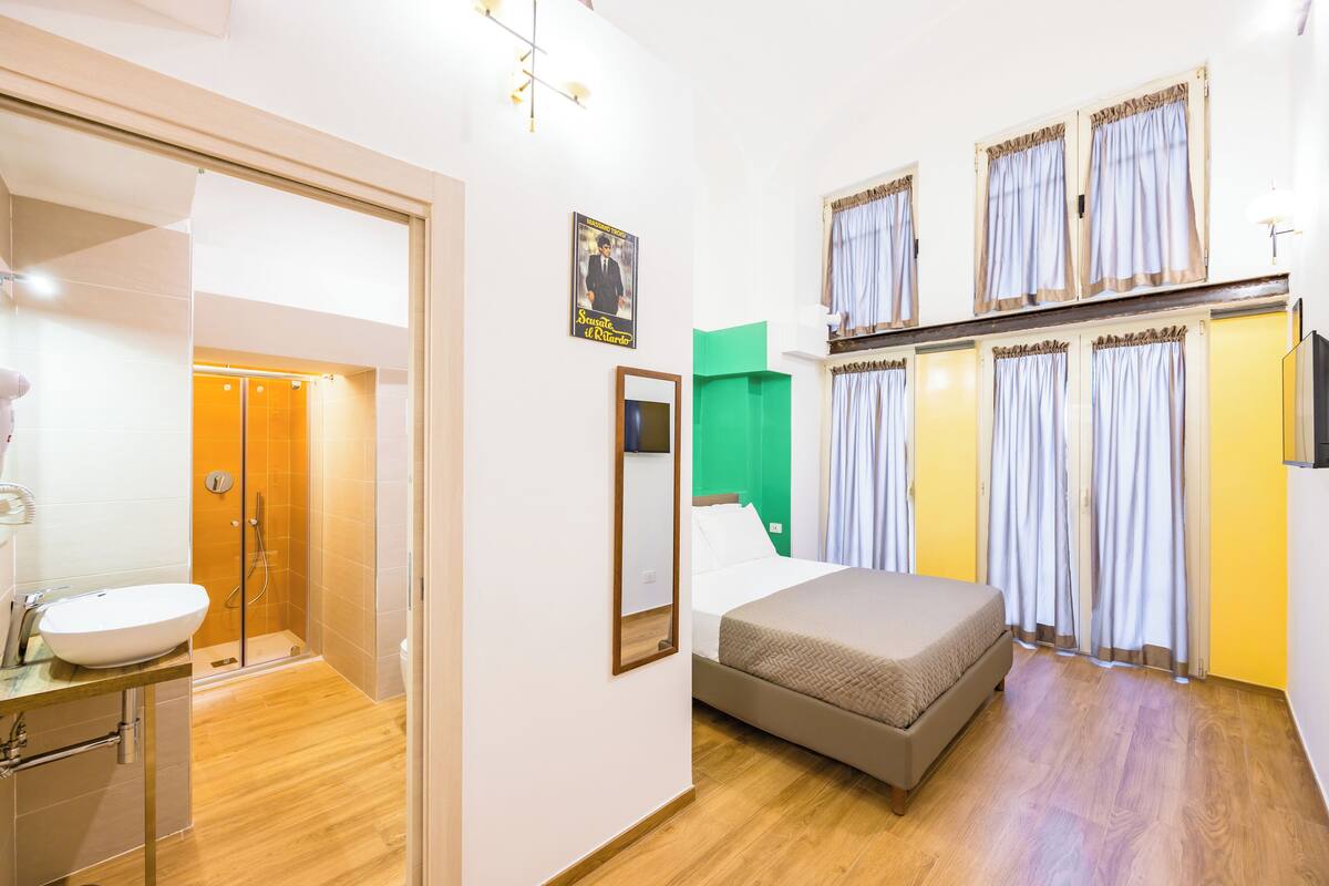 A hotel room with a bed, a bathroom, and a shower.