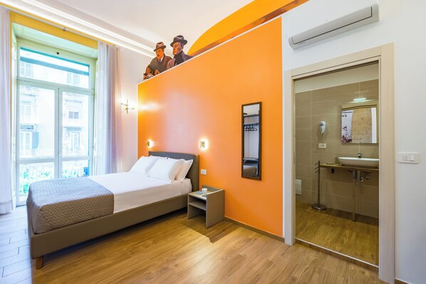 A hotel room with a bed, nightstand, and a bathroom with a sink and mirror. - Guest Rooms Bellini (Naples)
