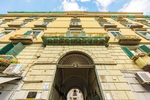 Ein Gebäude mit mehreren Balkonen, einem Bogenportal und Klimaanlagen.