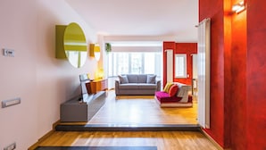 A modern living room with a grey sofa, a red sofa, and a coffee table. There is a large mirror on the wall and a window providing natural light. - Fresh and Trendy Flat at Vomero (Naples)