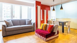 A modern living room with a grey sofa, a red and white sofa, and a dining area with a table and chairs. - Fresh and Trendy Flat at Vomero (Naples)