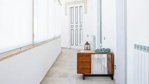 A hallway with a vintage wooden dresser, a clear glass cabinet, and a white door at the end.