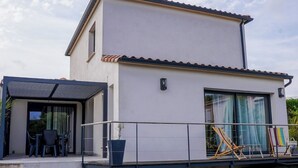 A modern two-story building with a flat roof and large windows. - 3-bedroom house (Les Mages)