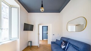 Ein modernes Wohnzimmer mit einem blauen Sofa, einem Fernseher und einem Spiegel an der Wand.