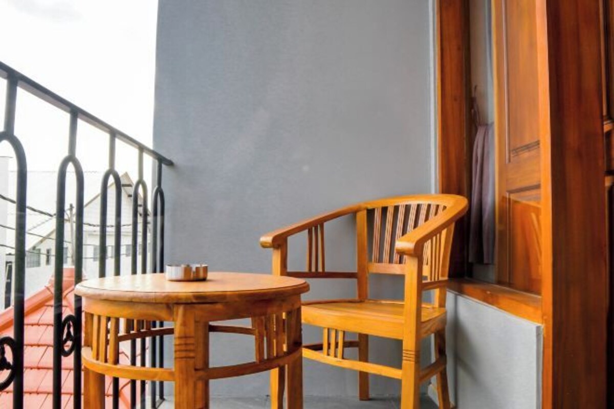 A wooden table and chair set on a balcony with a metal railing.