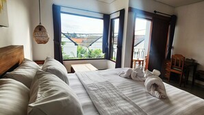 A hotel room with a bed, a desk, a chair, a TV, and a window with curtains. - Romansa Canggu (Canggu)