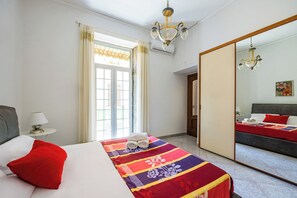 Une chambre d’hôtel avec un lit, une table de chevet, une lampe, une fenêtre avec des rideaux et un miroir.