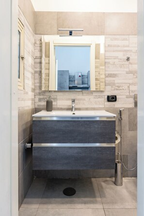Une salle de bain moderne avec un grand miroir, un lavabo et une douche.