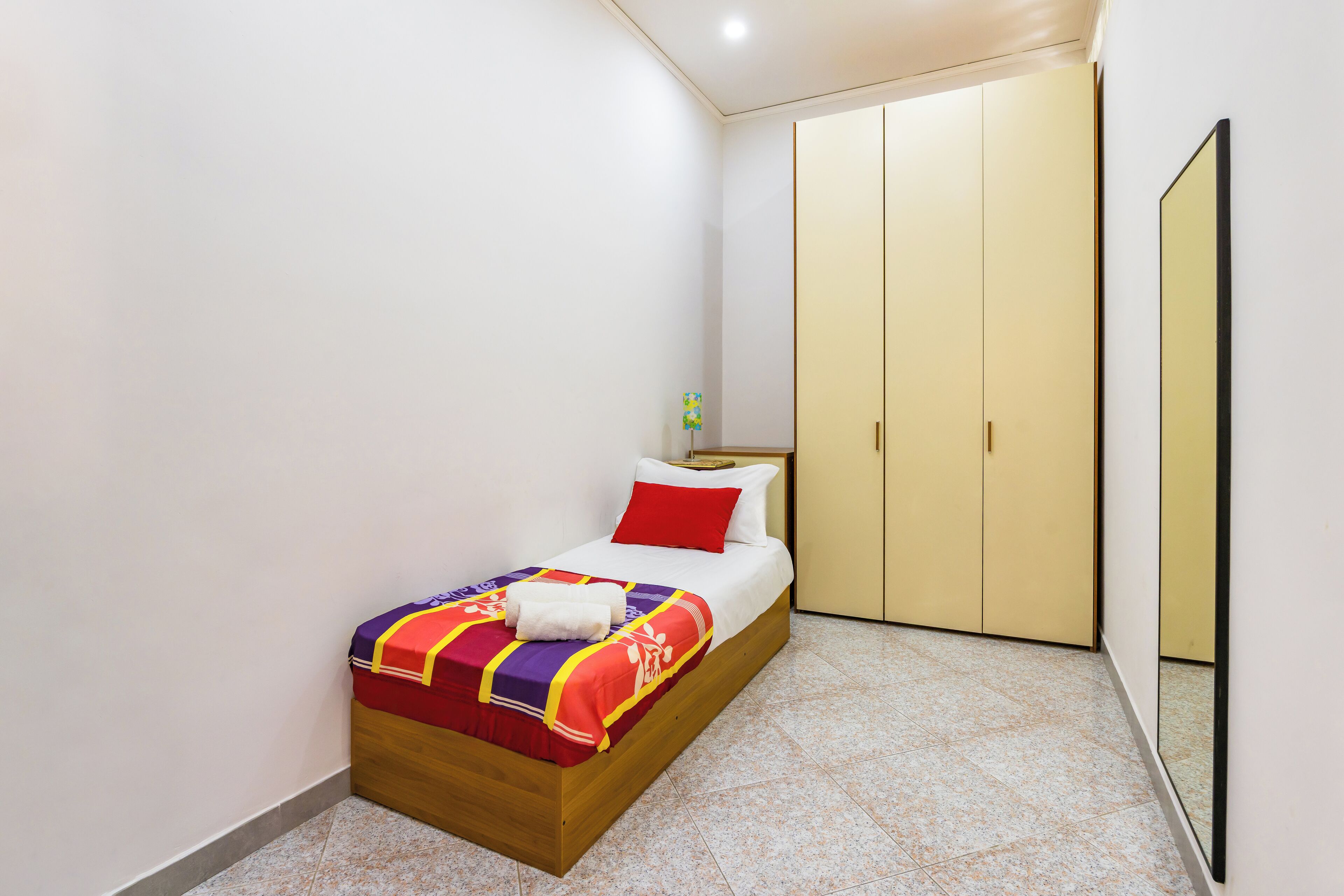 A bedroom with a bed, a wardrobe, and a mirror.