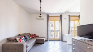 A modern living room with a sectional sofa, a flat-screen TV, and a wooden dresser. - Revolutionary Apartment Near Duomo Station (Naples)