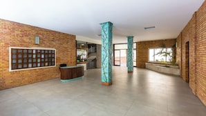 Un hall d’entrée spacieux, doté d’un comptoir de réception, de grandes fenêtres et de colonnes décoratives.