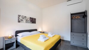 A neatly arranged hotel room with a bed, bedside tables, a wardrobe, and a painting on the wall.