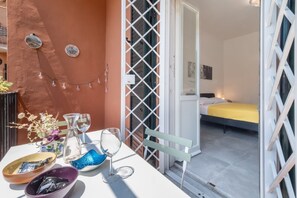 Een balkon met een tafel, glazen, een bloemenvaas en een schaal.